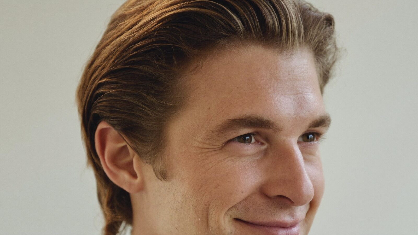 Smiling man in his 30s with swept-back hair and a soft, natural hairline