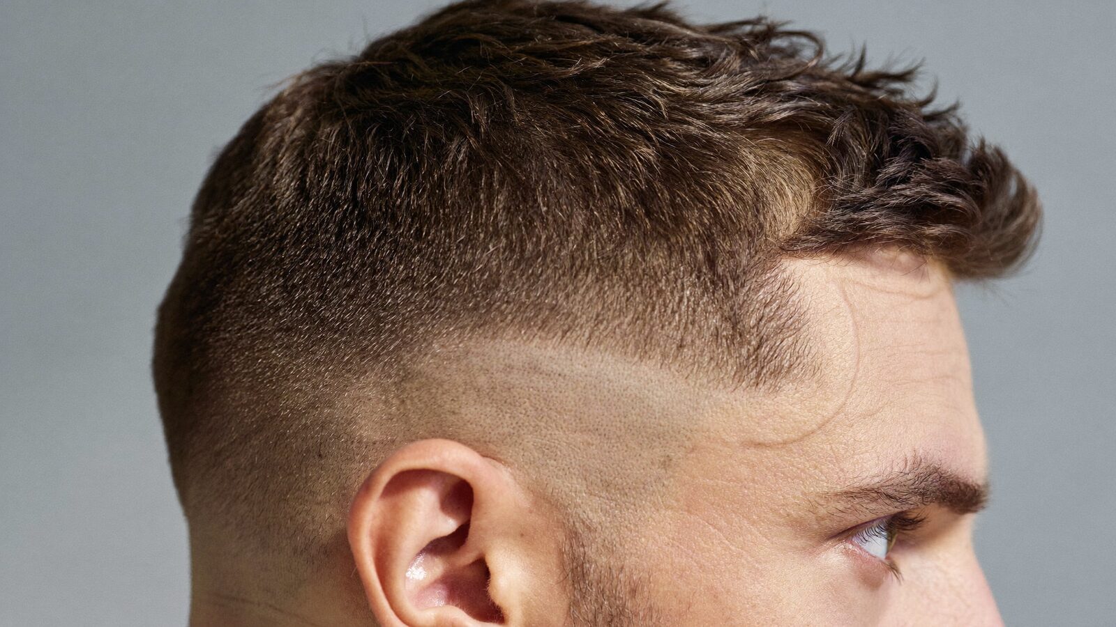 Side view of a man's natural temple and sideburn line with a short, tapered haircut